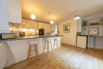 a kitchen with white cabinets and bar stools at Isgoed in Talsarnau