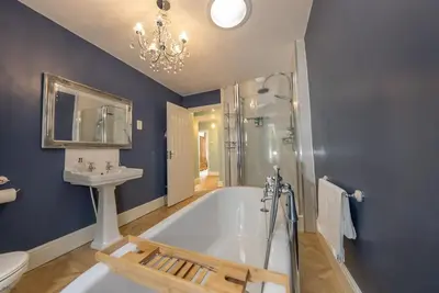 a bathroom with a tub and a sink and a mirror at Isgoed in Talsarnau