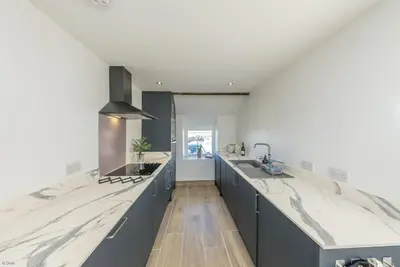 a kitchen with blue cabinets and marble counter tops at Bwthyn-Bennar in Dyffryn