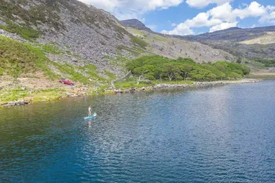 a person standing on a paddle board in a lake at Bwthyn-Bennar in Dyffryn