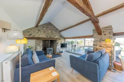 a living room with blue couches and a stone fireplace at Bwthyn-Bennar in Dyffryn