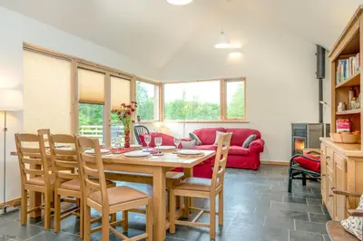 a dining room with a table and chairs and a red couch at Maes-Y-Coed in Dolgellau