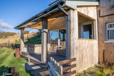a wooden cabin with a porch and a wooden fence at Allt-Goch in Llanbedr