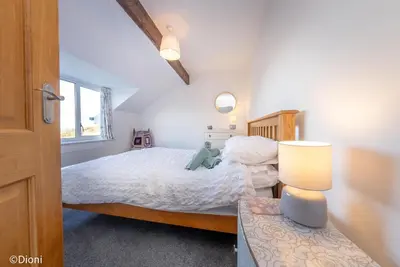 a bedroom with a bed and a table with a lamp at Allt-Goch in Llanbedr