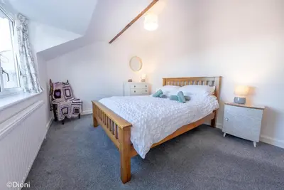 a bedroom with a bed and a dresser and a window at Allt-Goch in Llanbedr