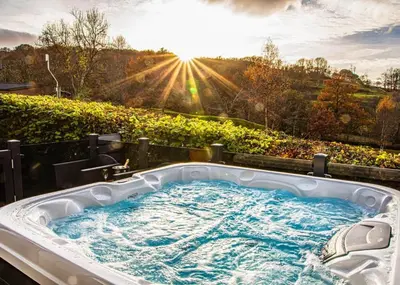 a jacuzzi tub with the sun in the background at Beautiful Home In Bala, Gwynedd W in Llanfor