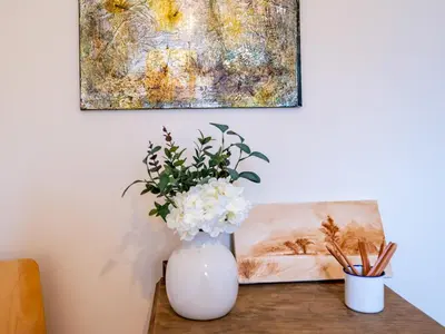 a vase with flowers on a table with a painting at Pass the Keys 3 Bedroom home local to Ludlow town centre in Ludlow
