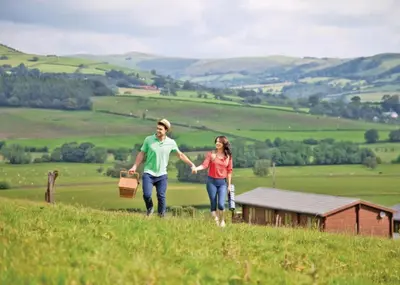 a man and woman walking down a hill holding hands at Trewythen Lodges in Towyn
