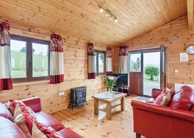 a living room with a red couch and a fireplace at Trewythen Lodges in Towyn