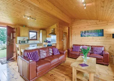 a living room with leather couches and a table at Trewythen Lodges in Towyn