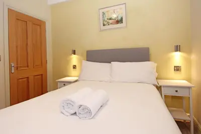 a bedroom with a white bed with towels on it at St John's Hill Apartments in Shrewsbury