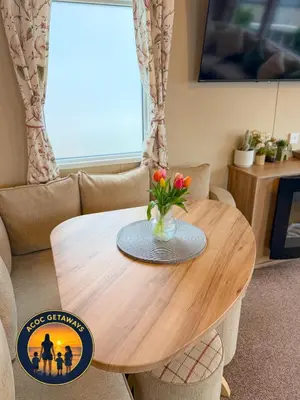 a wooden table with a vase of flowers on it at Preselli 5- Quay West Holiday Park, New Quay in New Quay