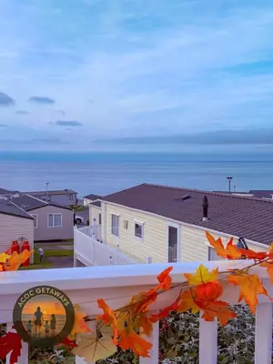 a view of the ocean from a balcony with autumn leaves at Preselli 5- Quay West Holiday Park, New Quay in New Quay