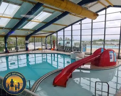 a swimming pool with a slide in a building at Preselli 5- Quay West Holiday Park, New Quay in New Quay