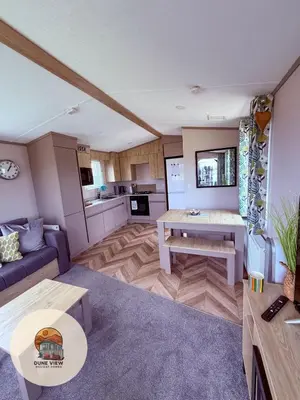 a living room with a couch and a table at Dune View Caravan in Ynys-lâs Station