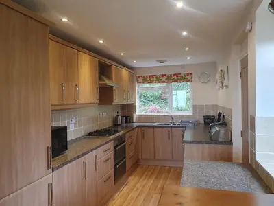 a large kitchen with wooden cabinets and a window at High Mead - family house with spectacular views in Aberdyfi