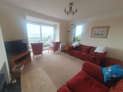 a living room with red couches and a flat screen tv at High Mead - family house with spectacular views in Aberdyfi