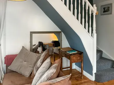 a living room with a couch and a stairway at Archers Cottage in Leominster