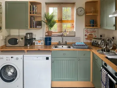 a kitchen with a sink and a washing machine at Archers Cottage in Leominster