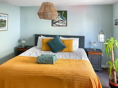 a bedroom with a large bed with a yellow blanket at Kookaburra Lodge in Brecon