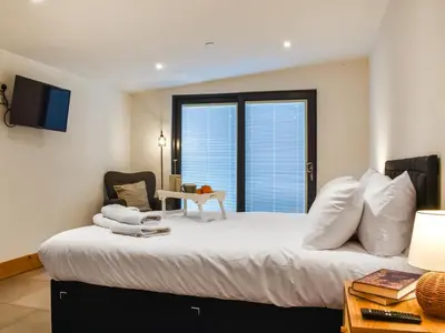a bedroom with a large white bed with a window at Acre Luxury Lodges-Cedar Lodge in Evenjobb