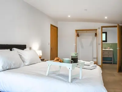 a bedroom with a white bed with a table on it at Acre Luxury Lodges-Cedar Lodge in Evenjobb