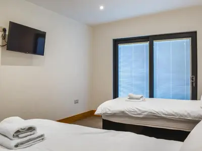 a room with two beds and a tv and a window at Acre Luxury Lodges-Cedar Lodge in Evenjobb