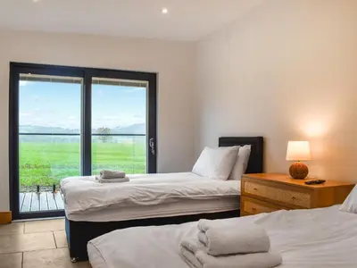 a bedroom with two beds and a window with a view at Acre Luxury Lodges-Cedar Lodge in Evenjobb