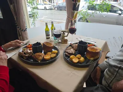 a table with two plates of food and glasses of wine at Twin room - The Unicorn Hotel in Llanidloes