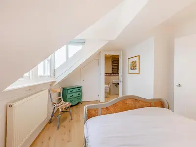 a bedroom with a bed and a chair in a attic at The Penthouse Westhaven in Aberdyfi