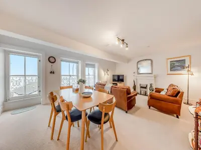 a dining room and living room with a table and chairs at The Penthouse Westhaven in Aberdyfi