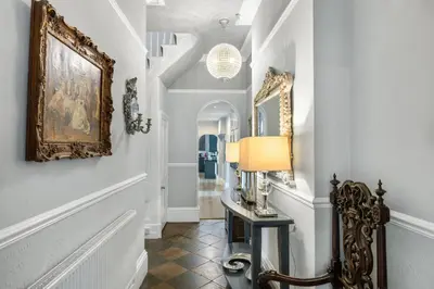 a hallway with white walls and a table with a lamp at The Topiary by Birch Stays in Wollaston