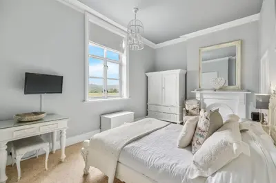 a white bedroom with a bed and a desk at The Topiary by Birch Stays in Wollaston