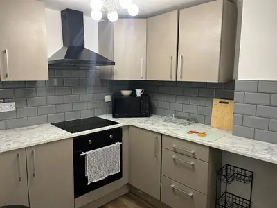 a kitchen with white cabinets and a stove top oven at Llangollen - House - Sleeps 8- Garden in Llangollen