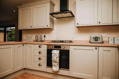 a kitchen with white cabinets and a stove top oven at Beacons View Luxury Lakeside Chalet- Trem Y Fan in Brecon