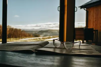 a pair of glasses sitting on top of an open book at Beacons View Luxury Lakeside Chalet- Trem Y Fan in Brecon