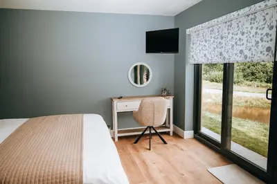 a bedroom with a bed and a desk and a window at Beacons View Luxury Lakeside Chalet- Trem Y Fan in Brecon