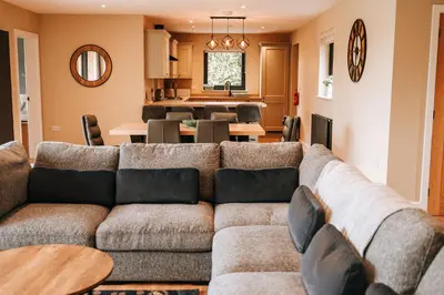 a living room with a couch and a dining room at Beacons View Luxury Lakeside Chalet- Trem Y Fan in Brecon