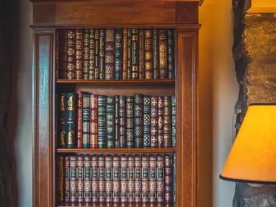 a book shelf filled with books next to a lamp at Noddfa Country House in Harlech