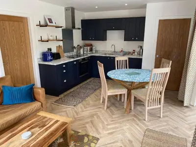 a kitchen and living room with a table and chairs at Serene Llanbedr Retreat with Garden View in Llanbedr