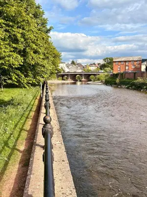 a fence next to a river with a bridge at Charming 2 bedroom cottage in Brecon - families and pets welcome! in Brecon