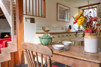 a kitchen with a wooden table with flowers on it at Finest Retreats - Pandy Farmhouse in Dolgellau
