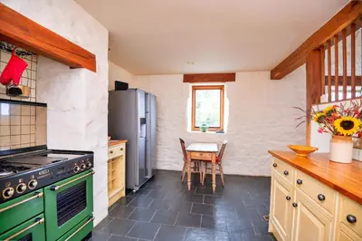 a kitchen with a green stove and a table at Finest Retreats - Pandy Farmhouse in Dolgellau