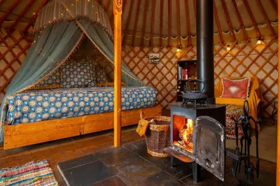 a fireplace in a yurt with a bed and a stove at Finest Retreats - Pandy Traditional Yurt in Dolgellau