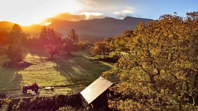 a farm with a tractor in a field with a mountain at Finest Retreats - Waen Fechan in Dolgellau