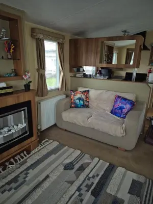 a living room with a couch and a fireplace at The Dancing Dolphin, 124 Aber Bay Holiday Park, Clarach, Aberystwyth in Aberystwyth