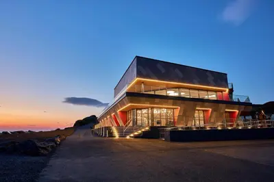 a large building with a sunset in the background at The Dancing Dolphin, 124 Aber Bay Holiday Park, Clarach, Aberystwyth in Aberystwyth