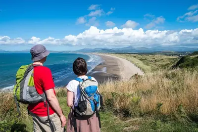 two people standing on a hill looking at the beach at Beudy-Talsarnau in Talsarnau