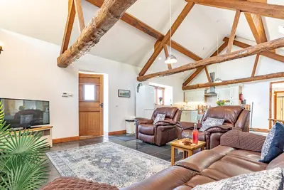 a living room with leather furniture and a tv at Beudy-Talsarnau in Talsarnau
