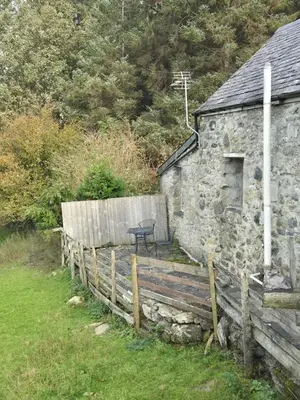an old stone house with a wooden fence and a table at The Old Barn in Bettws Gwerfil Goch